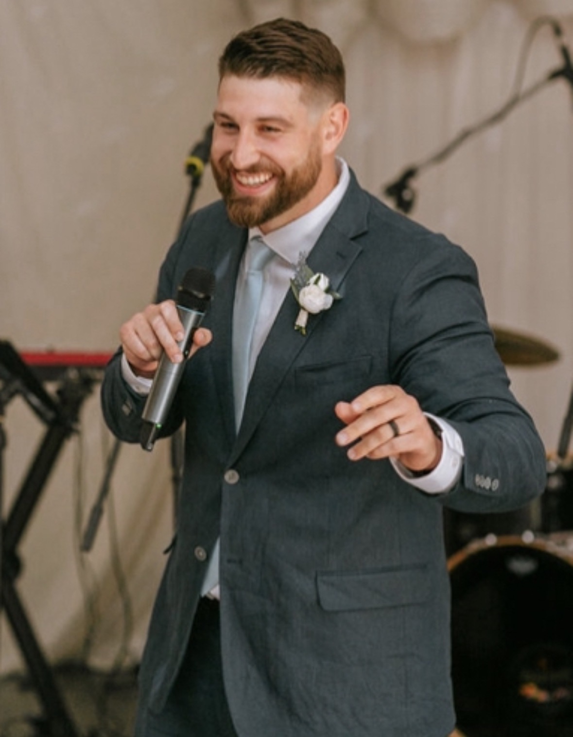 Pete speaking at an event, holding a microphone and smiling